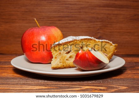Fresh apples and a piece of apple pie sprinkled with powdered su