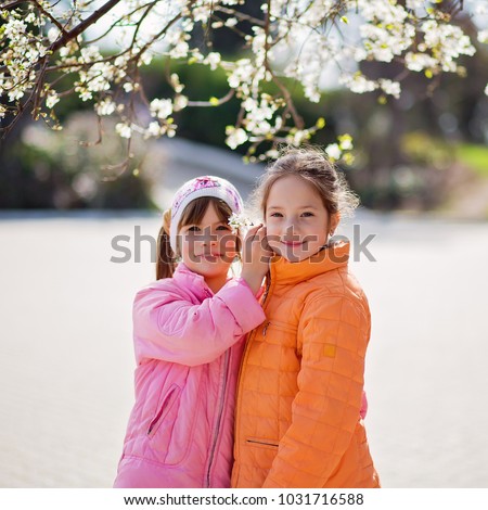 Cheerful little girls outside in the spring garden having fun