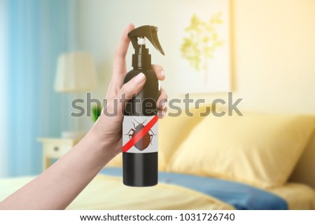 Woman holding bottle of anti bed bug detergent in bedroom