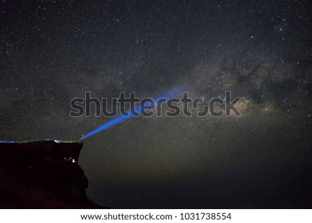 Traveller Standing on rocky mountain peak light up in hand to Milky Way Galaxy, success, winner, leader concept.