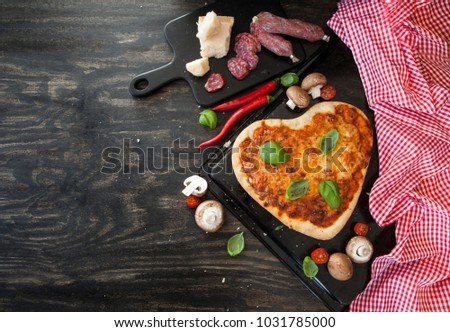 Pizza Margherita in a heart shape on rustic wooden background