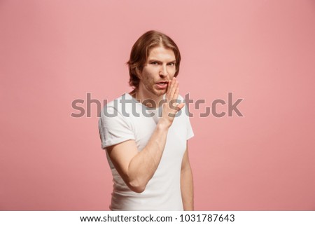 Secret, gossip concept. Young man whispering a secret behind her hand. Business man isolated on trendy pink studio background. Young emotional man. Human emotions, facial expression concept.