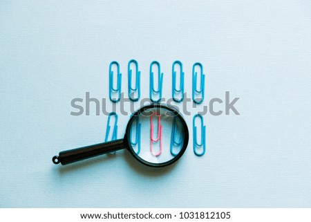 a magnifying glass and paper clips on a blue background.