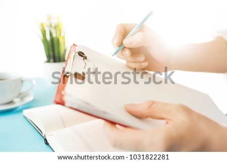 Male hands holding pen, writing. Side view on man on trendy color blue desk. Man and stilish workplace.
