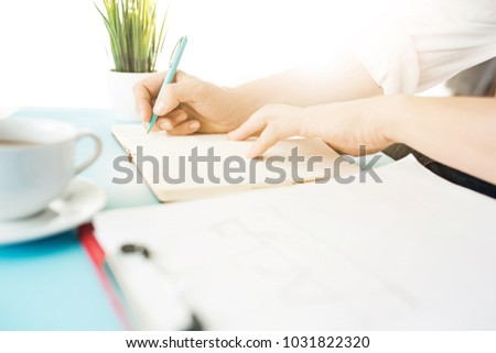 Male hands holding pen, writing. Side view on man on trendy color blue desk. Man and stilish workplace.