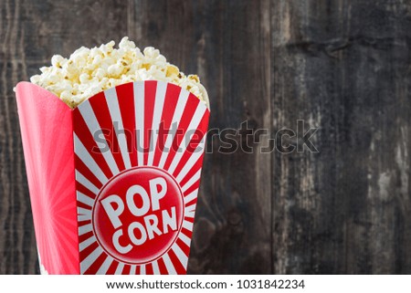 Popcorn inside the packaging striped on wooden table background. Copyspace