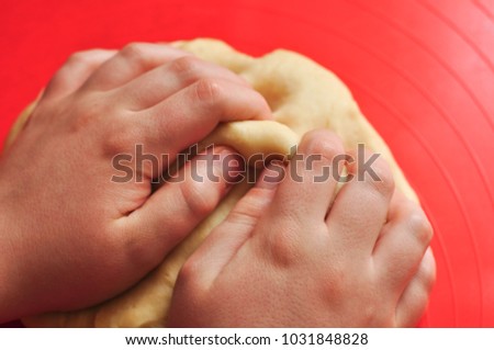 young children's close up hands kneading dough on the red placement , baking Christmas cookies / sweets