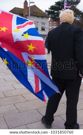 Boris Johnson in black suit waving UK flag with EU stars Royalty-Free Stock Photo #1031850760