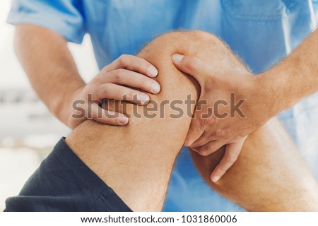 Physiotherapist doing healing treatment on patient leg. Therapist wearing blue uniform. Osteopathy, Chiropractic leg adjustment Royalty-Free Stock Photo #1031860006