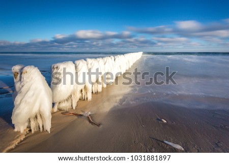 Winter landscape at the sea. Frozen wooden breakwaters line at Baltic Sea. Morning at Chalupy, Poland.