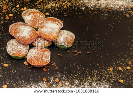 Exposition of cupcake with cup of coffee, cinnamon and sugar on black table, very tasty cakes for any celebration.