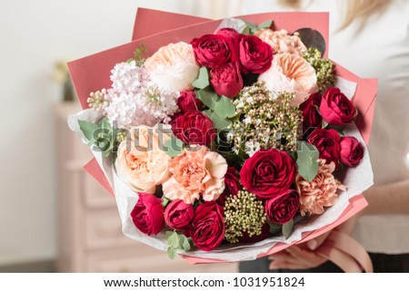 bouquet of highly red coloured . beautiful luxury bunch of mixed flowers in womans hand. the work of the florist at a flower shop.