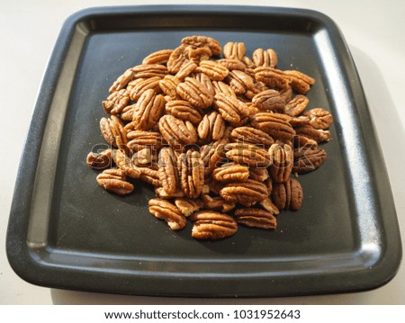 A bunch of nuts pecan on a black plate. Close-up photo