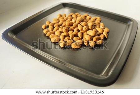 A bunch of nuts of almonds on a black plate. Close-up photo