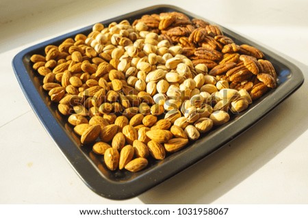 Nuts almonds, pistachios and pecans on black plate, close-up, set. 