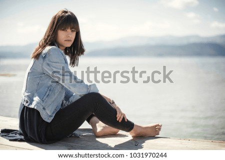 Young beautiful woman posing on pear. Conceptual photo of a holiday by the lake.
