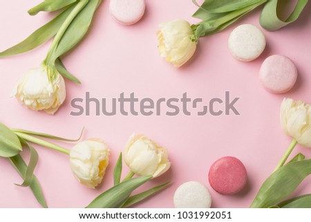 Spring morning concept. Flat-lay of white flowers and macarons over light pink background