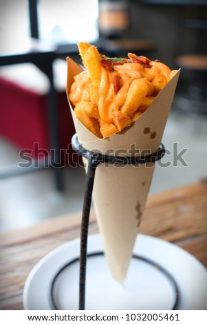Delicious french fries topping with cheddar cheese and crispy bacon in a paper cone Royalty-Free Stock Photo #1032005461