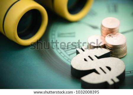 Yellow binoculars and stack of coins, wooden dollar with copy space using as background finding, sale, buy, trade, business time concept.