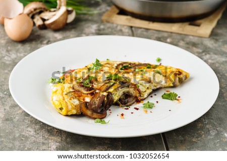 Fresh homemade omelette with mushrooms, feta cheese and herbs. Royalty-Free Stock Photo #1032052654