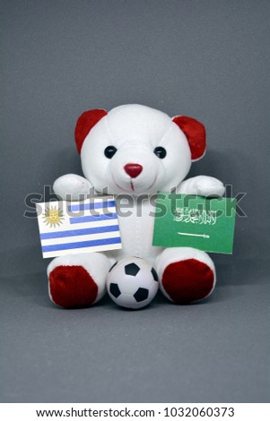 Teddy bear holding Uruguay and Saudi Arabia Flag with a football