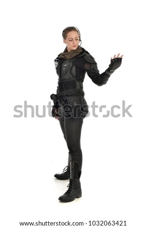 full length portrait of female  soldier wearing black  tactical armour and headset standing pose  with arms raised, isolated on white studio background.