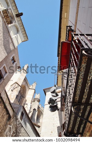 old kitchen utensils hanging on the facade for advertising,Photographs in angle against chopped streets and facades of Toledo, Spain, narrow street, windows and balconies with wrought iron grills, art