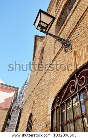 Photographs in angle against chopped streets and facades of Toledo, Spain, narrow street, windows with wrought iron grills, art, lamppost,  in the background the cathedral,