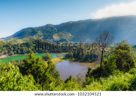 Scenery of two colored lake Telaga Warna, Dieng plateau, INdonesia on daylight with clear blue sky and surrounded with green forest mountain.