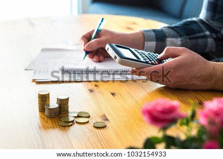 Man using calculator and counting budget, expenses and savings. Low income family living cost and rising prices concept. Calculating and budgeting. Making retirement plan. Writing notes on paper.  Royalty-Free Stock Photo #1032154933
