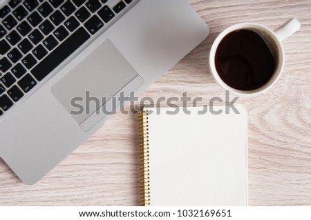 Notepad, laptop with pencil and coffee cup on wood table