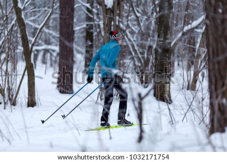 Photo from back of male skier in forest in winter