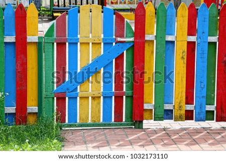 Colored wooden fence with a closed gate
