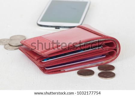 money with credit card in red purse and coins mobile phone on table white