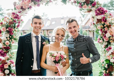 Friend and brother greet brides with the wedding day. The bride and groom. Newlyweds. Wedding ceremony under the arch decorated with flowers and greenery.