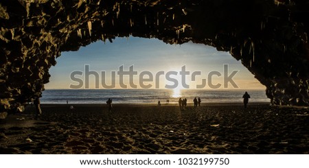 A view from Hálsanefshellir Cave on iceland with the people in the front and sunset in the back.