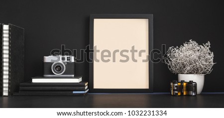 Picture frame, books, supplies and a camera on a desk. Black color mock up workspace.