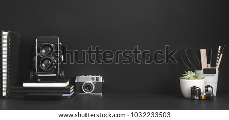 Cameras, books and supplies on a black background with copy space. Mock up