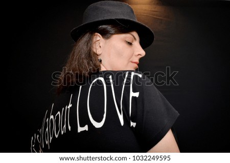 gorgeous woman with long dark hair posing in studio with glasses and black hat on black background 