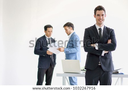 Successful businessman standing in front of employee in background office