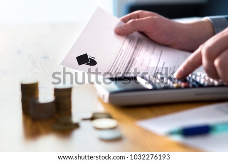 Man counting college savings fund, tuition fee or student loan with calculator. Education price and expenses concept. Money and papers on table. Calculating budget and planning finance. Royalty-Free Stock Photo #1032276193
