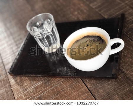 Cup of coffee on a wooden table with glass of water 