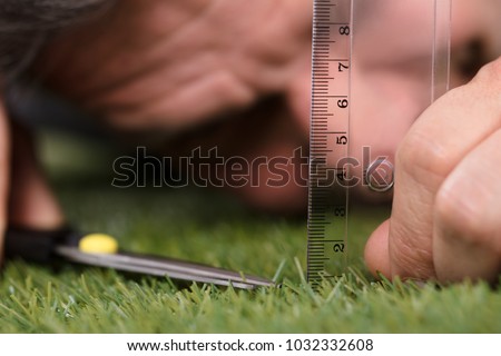 Close-up Of A Man Using Measuring Scale While Cutting Grass With Scissors Royalty-Free Stock Photo #1032332608