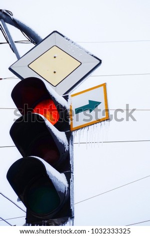 Traffic light on the street with ice and snow in the winter. Frozen road signs.