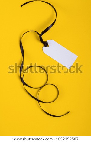 White tag with black ribbon on yellow background