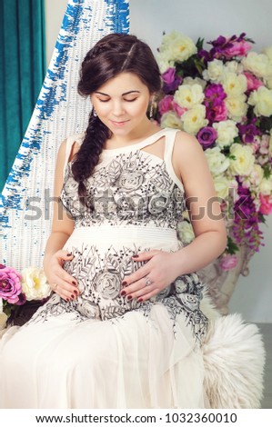 Studio portrait of pregnant woman holding her belly