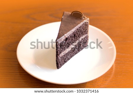 A piece of chocolate cake isolate in white plate on wooden background with copy space.