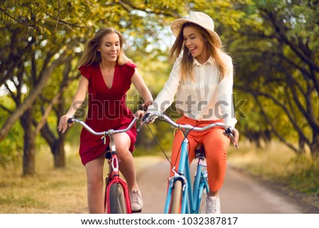Beautiful sisters riding bicycles in park