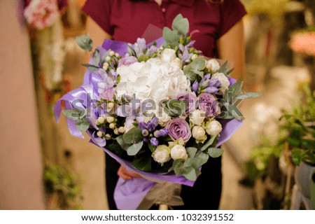 girl holding a stylish bouquet of roses, hydrangea, orchid, eustoma, peonies in purple wrapping paper