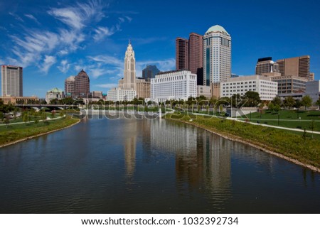 The skyline of downtown Columbus, Ohio along the Scioto River is crisp and clear.  Wispy clouds in the sky add drama to the cityscape.